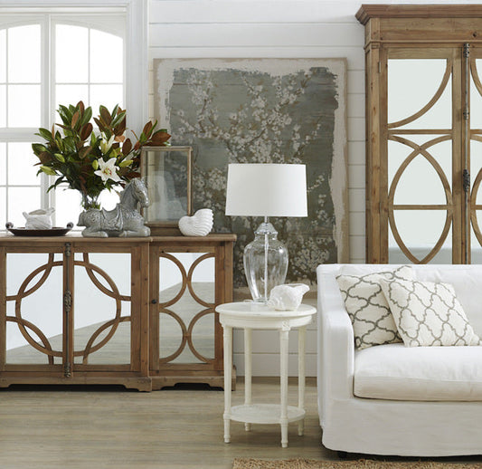 A sleek, white console table with drawers, styled in a living room with a table lamp and a stack of books. Shop modern consoles at The Epic.